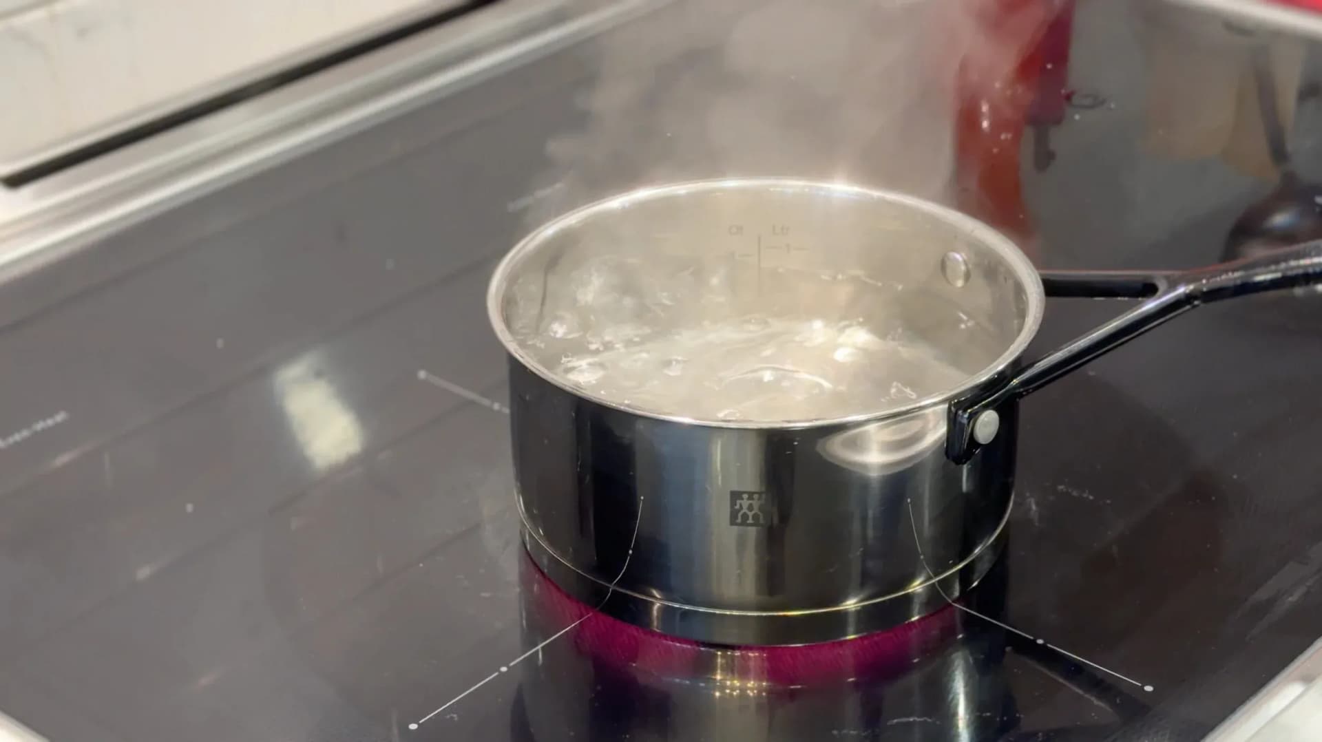 Pot of boiling water with beet slices on an induction cooktop for blanching.