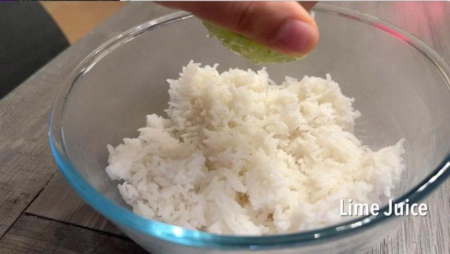 Cooked white rice in a glass bowl with lime juice being added, labeled for cilantro-lime rice recipe.