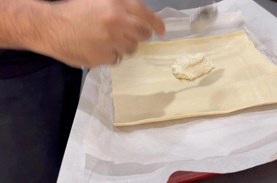 Ricotta mixture spread on puff pastry sheet with border left around edges for folding.