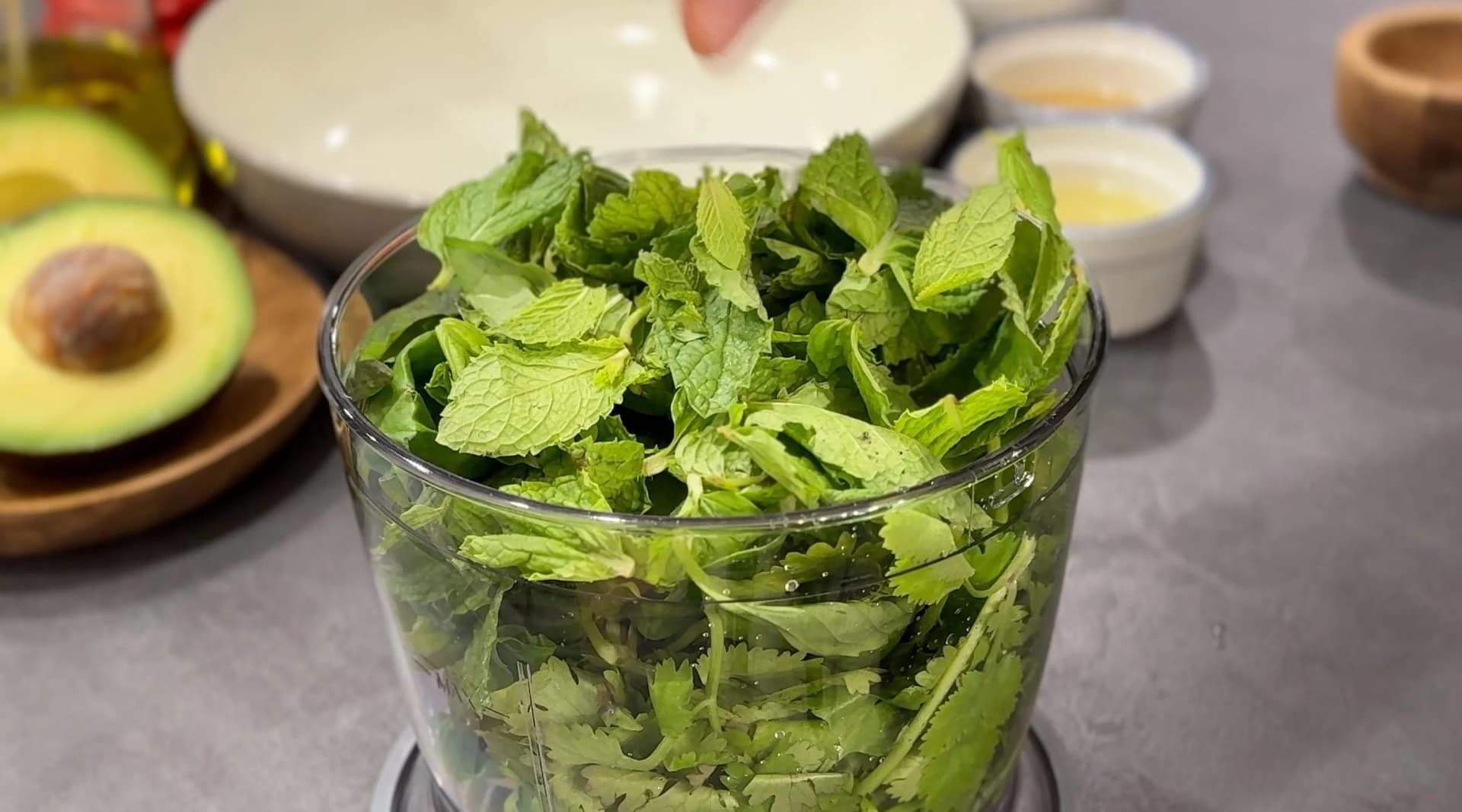 Fresh herbs chopped in a food processor bowl for green goddess dressing