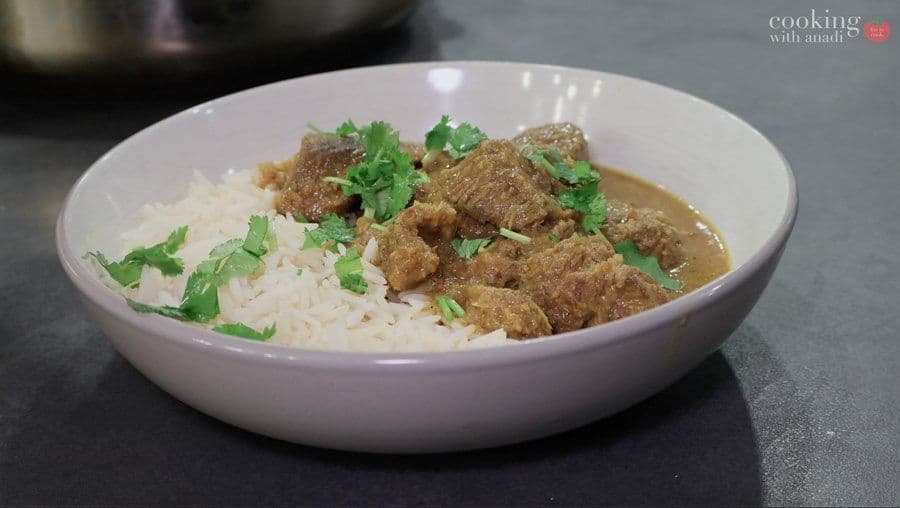 Balinese beef rendang served over white rice in a bowl, garnished with fresh cilantro.