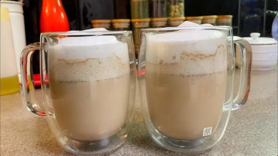 Two glass mugs of French vanilla cappuccino with layered milk foam and coffee, topped with cinnamon.