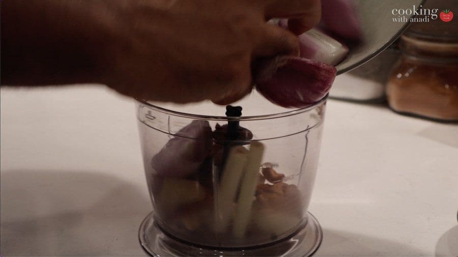 Food processor with spice paste ingredients being blended for Balinese beef rendang base.