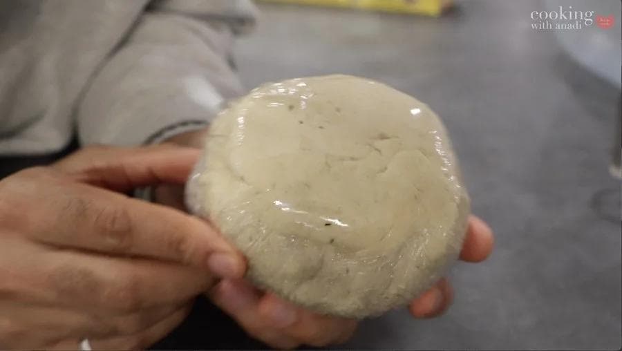Hands holding a smooth, pale dough ball that has rested and hydrated for the gluten-free strukli recipe.