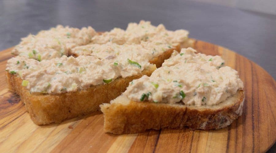 Tuna salad spread on toasted bread slices, garnished with chopped green onions.