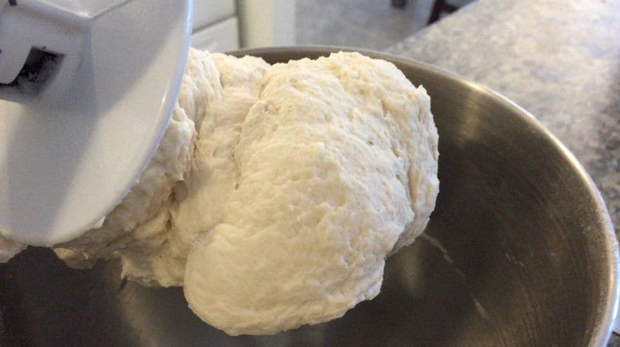 Soft, tacky naan dough being kneaded in a stand mixer bowl