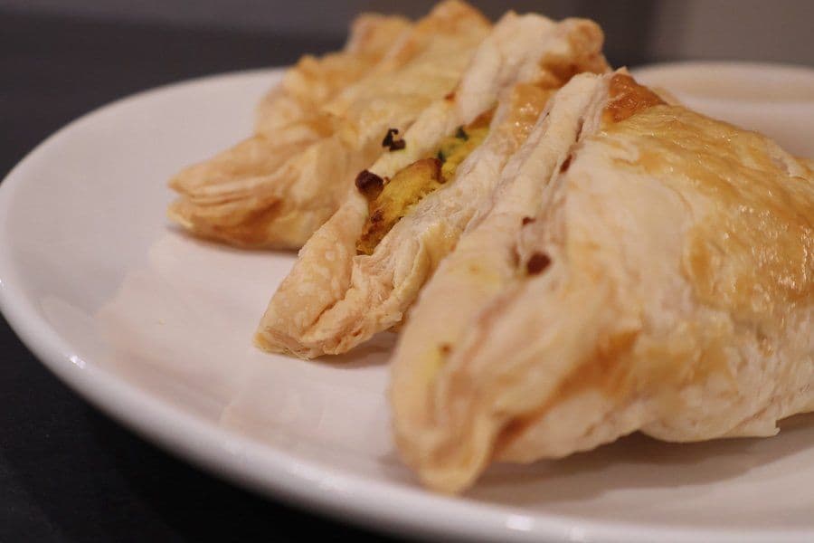Three golden air fryer aloo patties with crispy puff pastry and visible potato filling on a white plate.