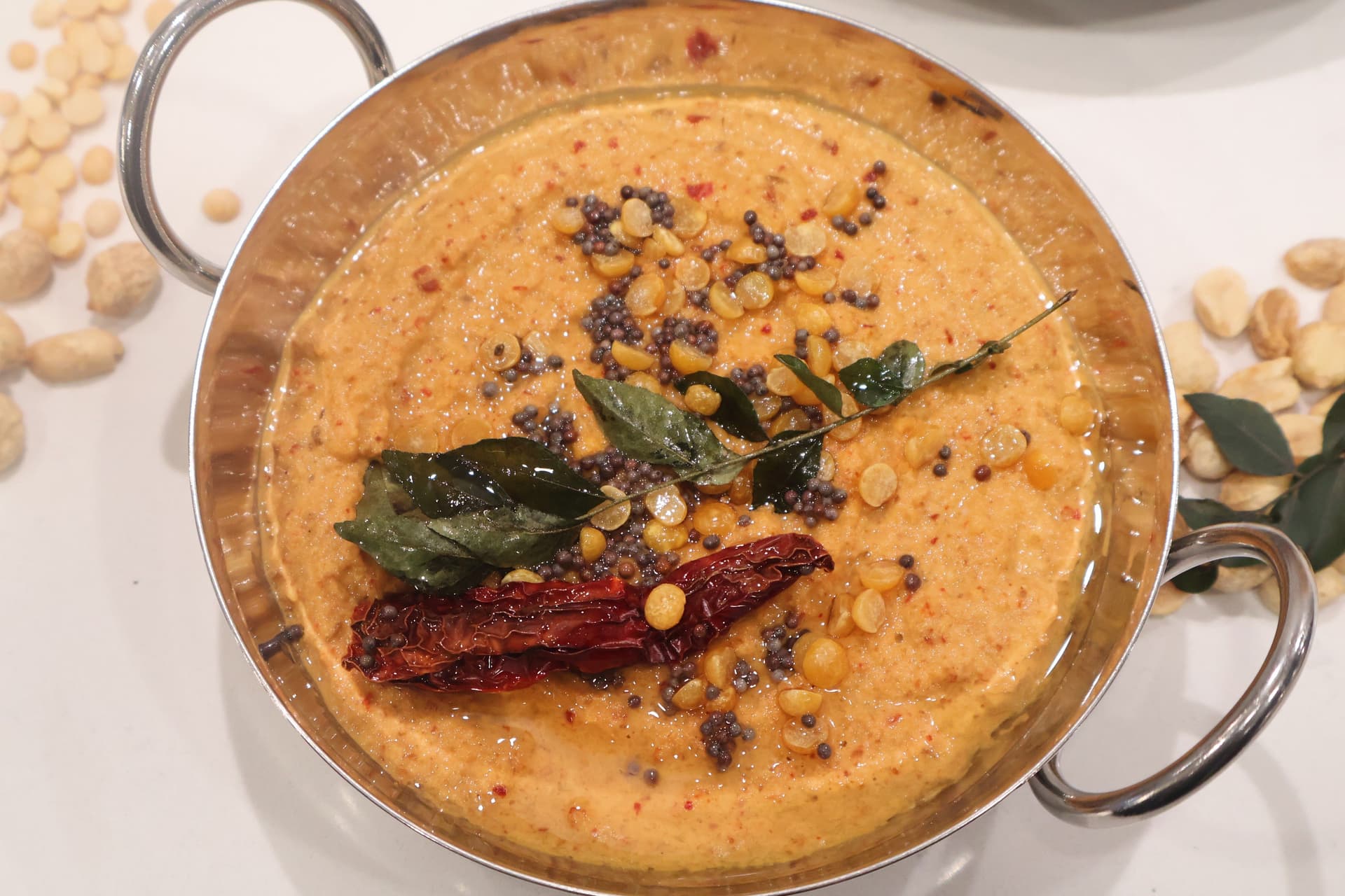 South Indian roasted peanut chutney garnished with mustard seeds, curry leaves, and dried red chili in a serving bowl.