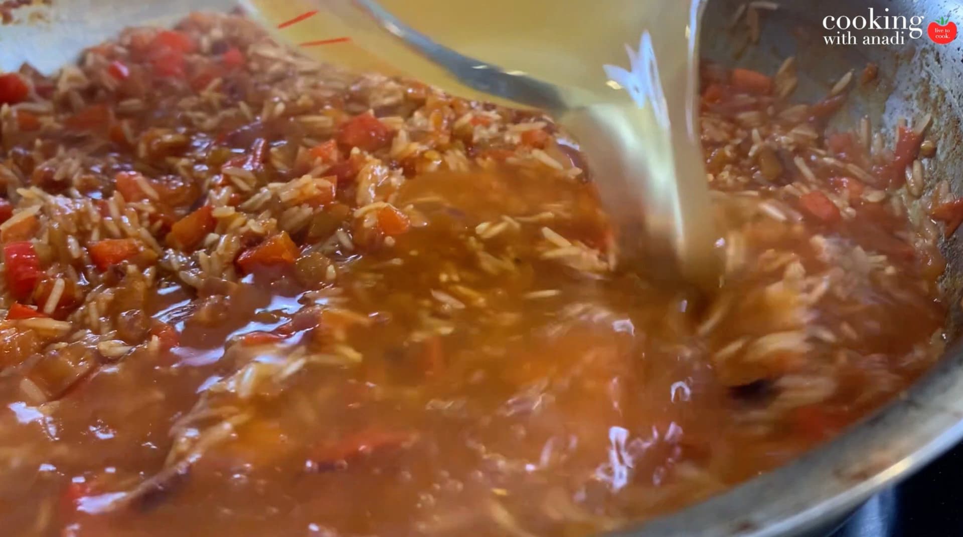 Tomatoes and rice simmering together in a pot with a glossy, reddish-brown sauce coating the grains.