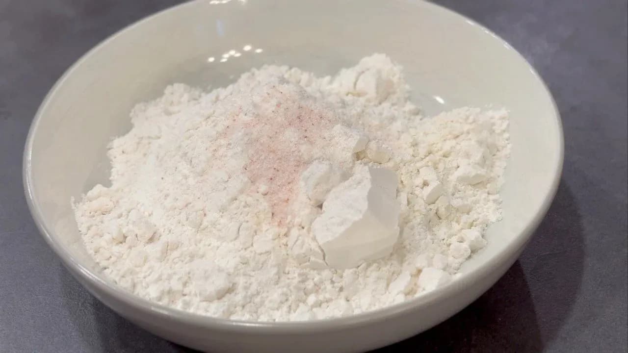 Flour, salt, and water mixed in a white bowl for momo dough preparation.