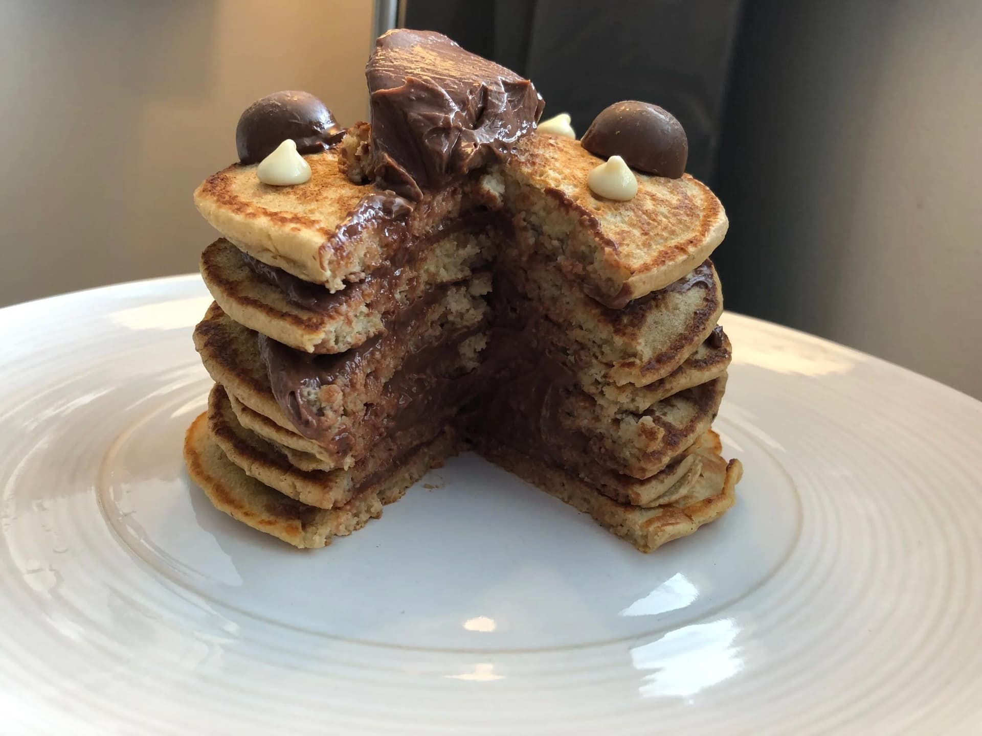 Chocolate ice cream sandwich pancakes stacked and split open, filled with chocolate spread and topped with Aero Mini pieces.