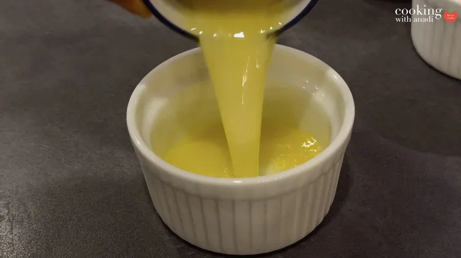 Melted butter and olive oil mixture being poured into a white ramekin for brushing potatoes.