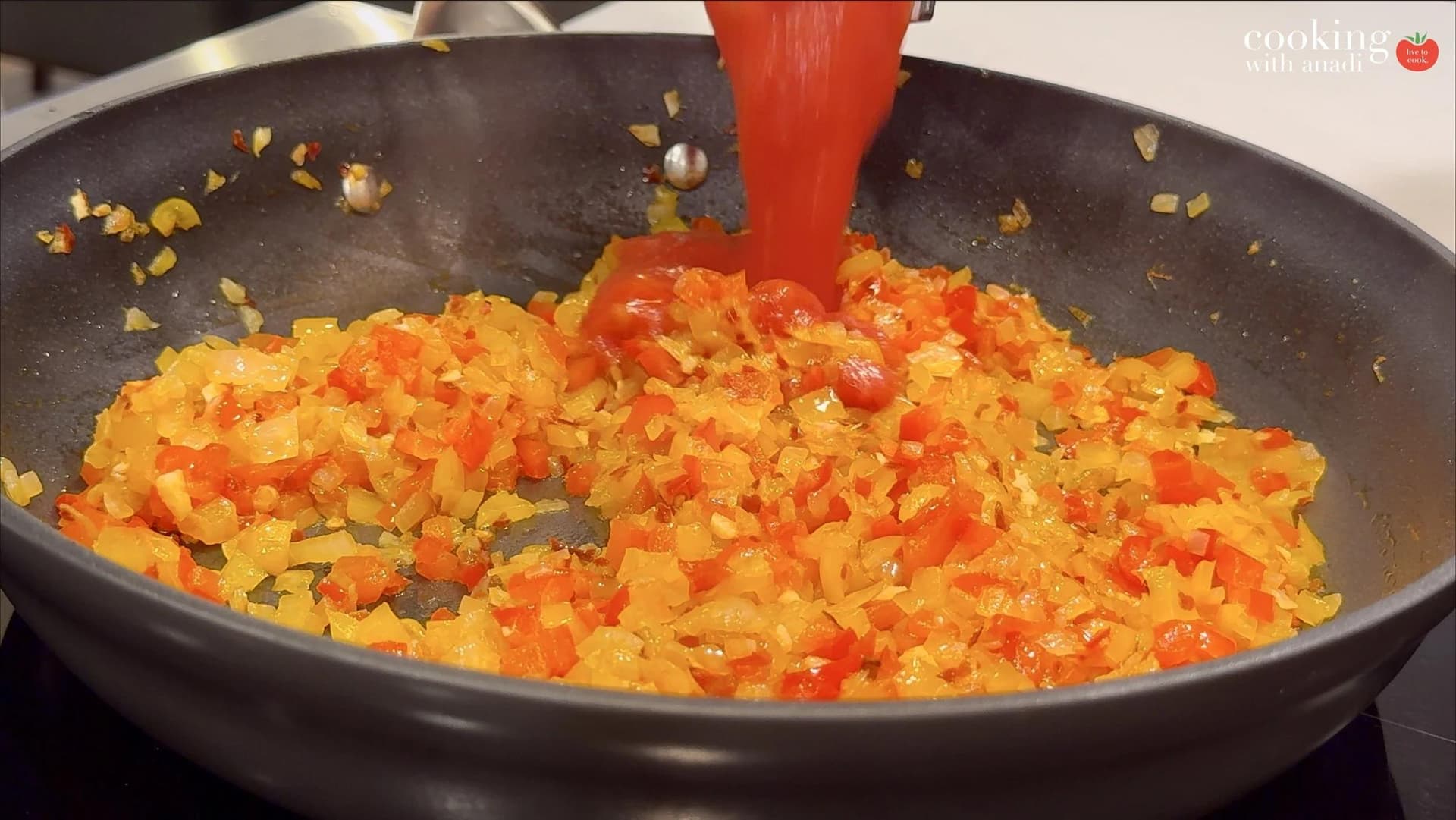 Crushed tomatoes being poured into a skillet of sautéed onions and diced red and yellow bell peppers.