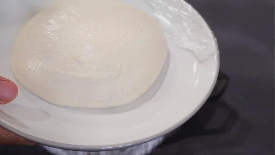 Proofed pizza dough in an oiled cast iron pan ready to be stretched.