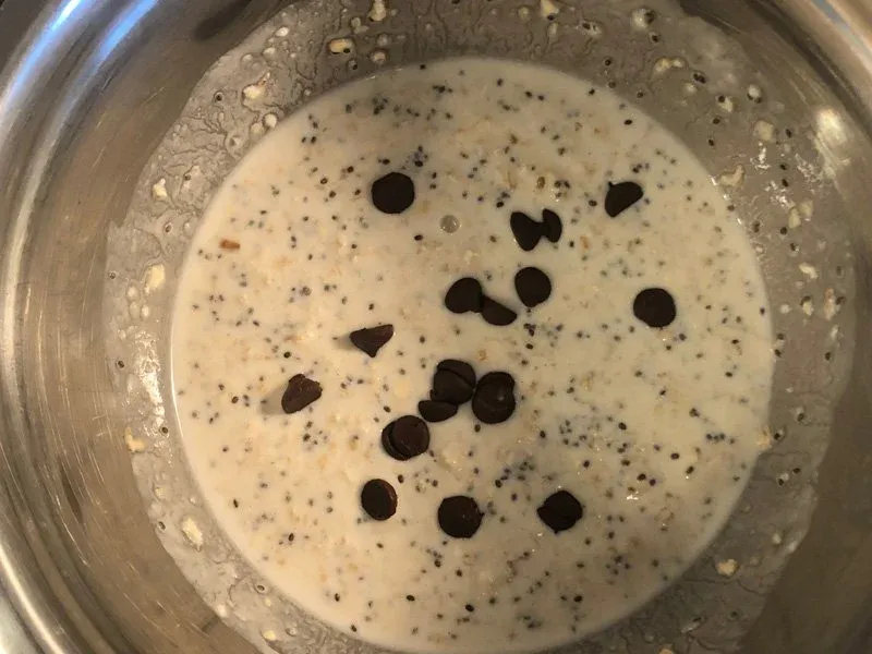 Creamy oat mixture in a bowl with chocolate chips scattered on top before folding.