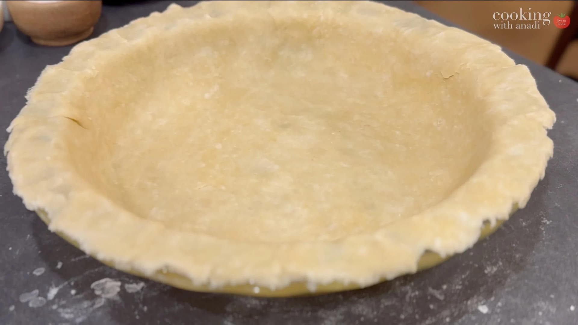 Unbaked pie crust fitted in a 9-inch pie dish on a dark work surface.