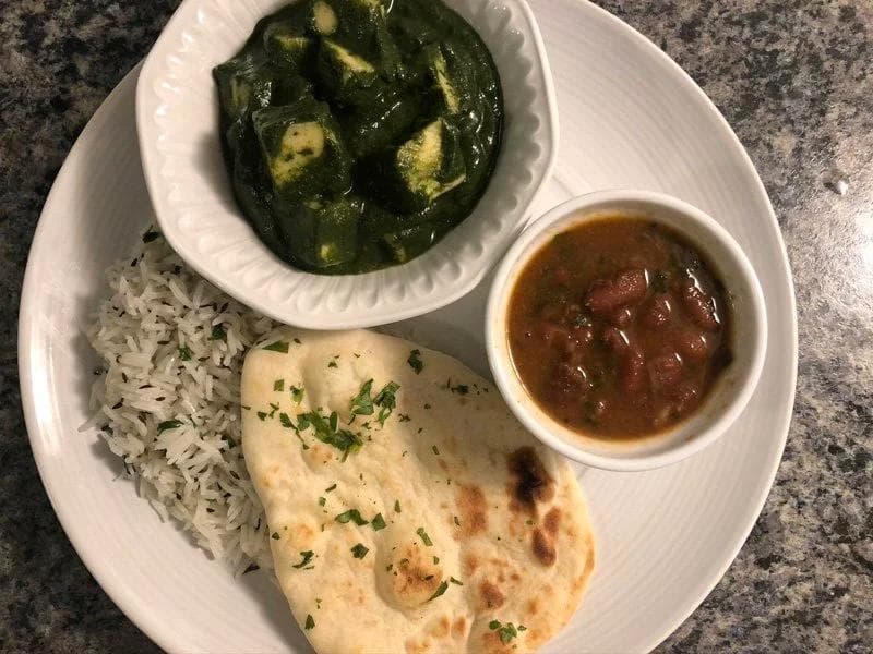 Instant Pot Palak Paneer served with basmati rice, naan bread, and red sauce on a white plate.