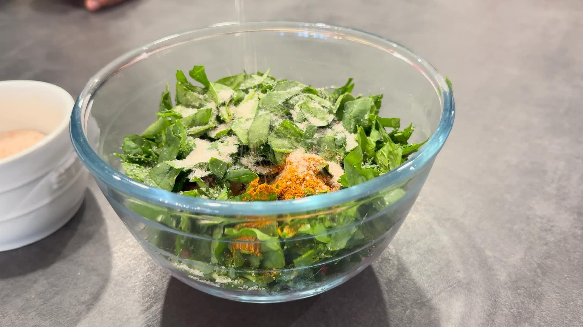 Fresh spinach and ground turkey mixture with seasonings in a glass bowl before forming burger patties
