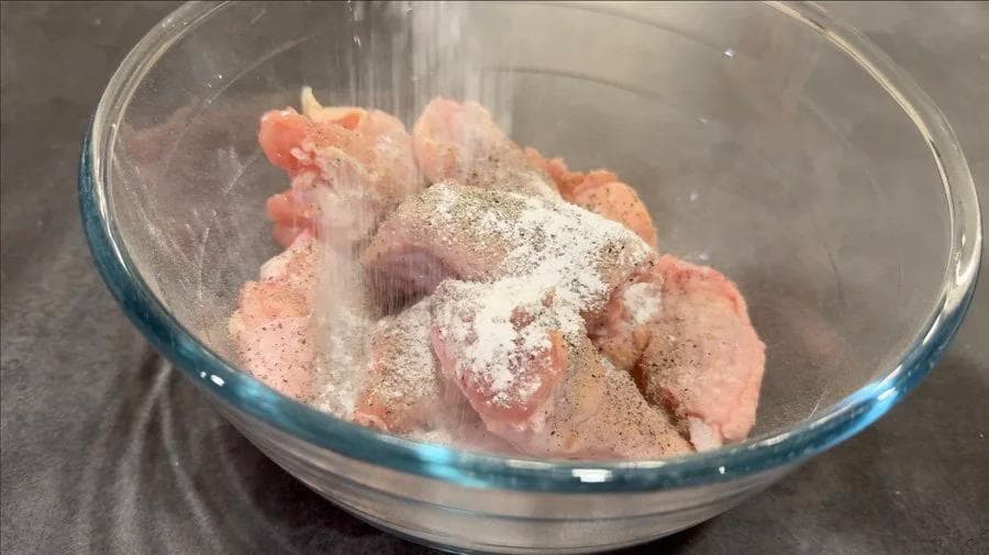 Raw chicken wings seasoned with salt, pepper, and baking powder in a glass bowl.