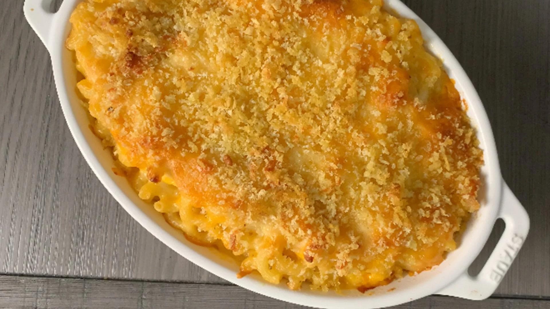 Baked mac and cheese in a white oval dish with a golden breadcrumb crust topping.