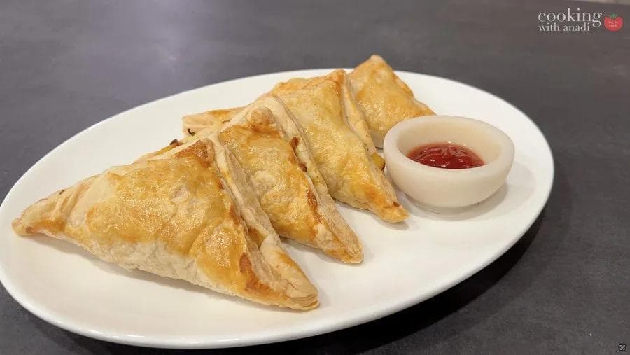 Golden-brown air fryer aloo patties arranged on a white plate with a small bowl of red dipping sauce.