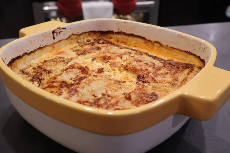 Baked gluten-free strukli in a yellow casserole dish with golden-brown cheese topping.