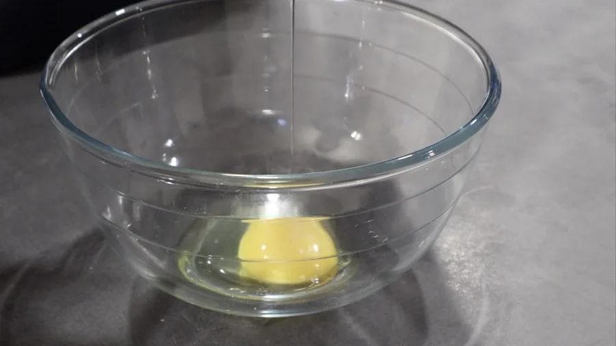 Wet ingredients mixed in a glass bowl: egg, egg white, maple syrup, pumpkin puree, coconut oil, and vanilla extract.