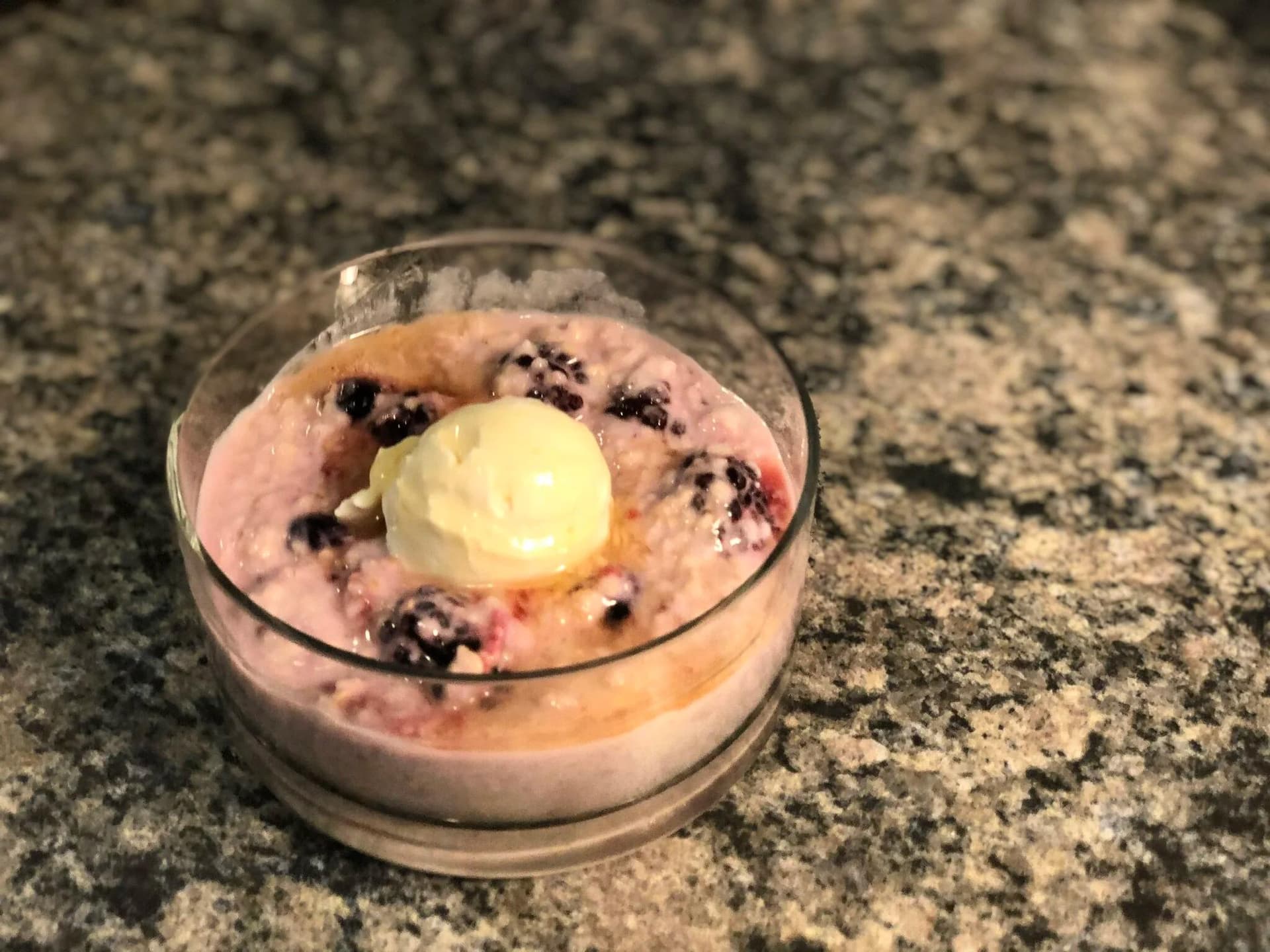 Hot berry cheesecake oatmeal topped with cream cheese and honey drizzle in a bowl.