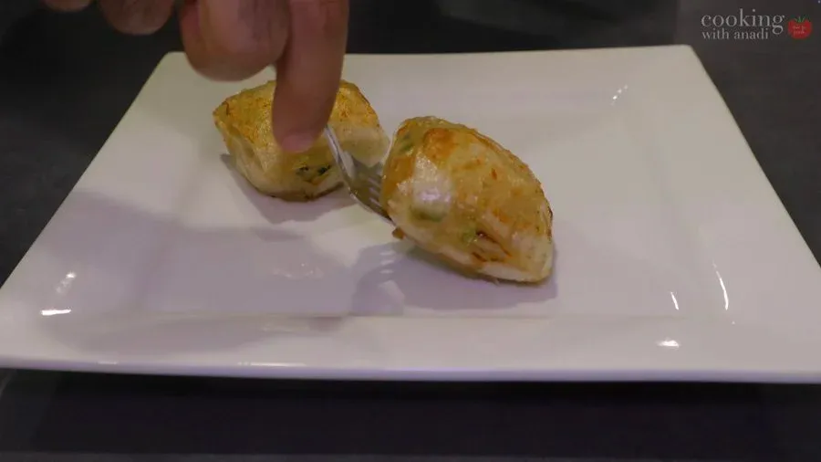 Golden, crispy air fryer rice paper chicken dumplings on a white plate, being broken open to show the filling inside.