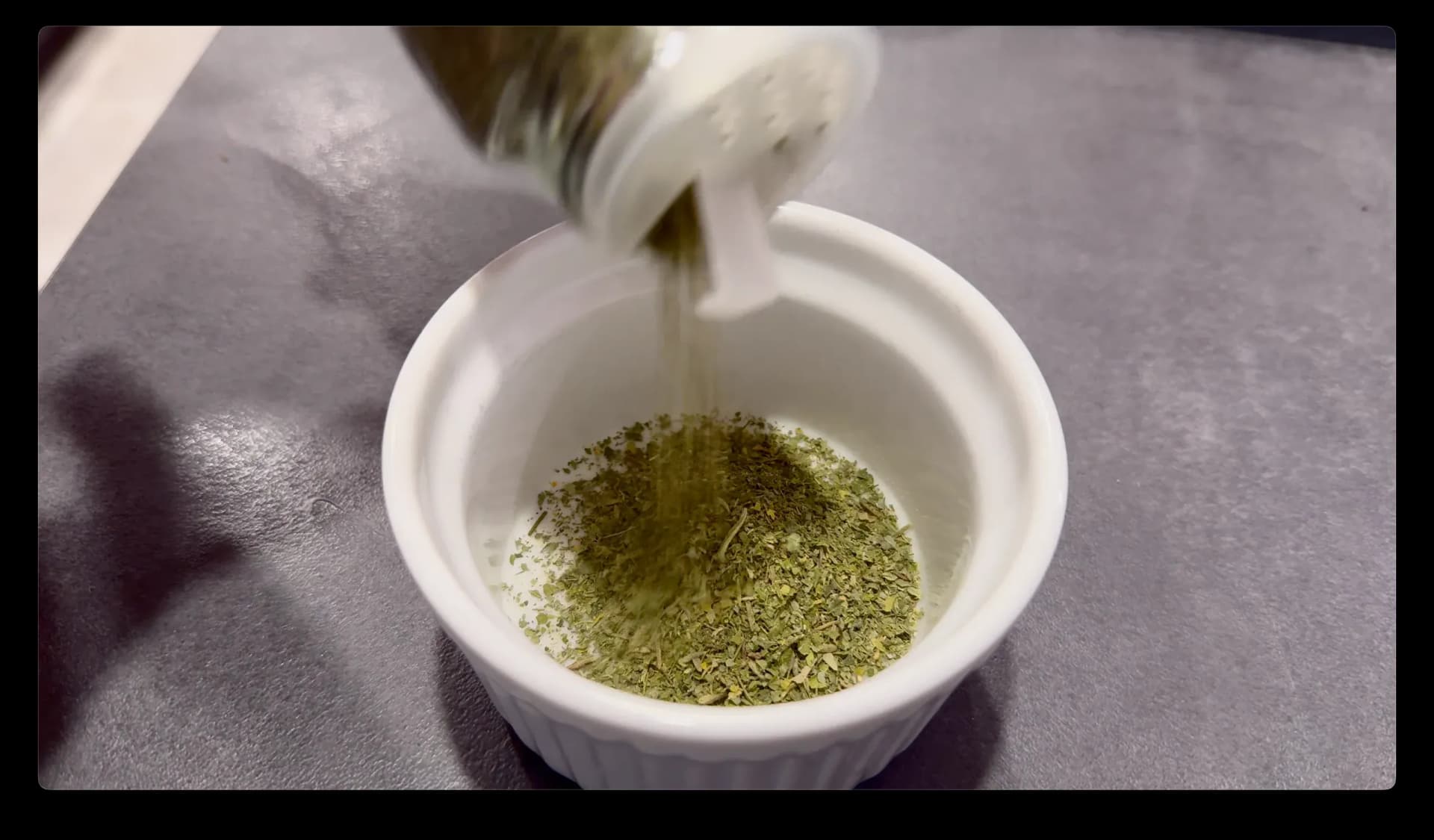 Herb seasoning paste being poured into a white bowl for an air fryer chicken recipe