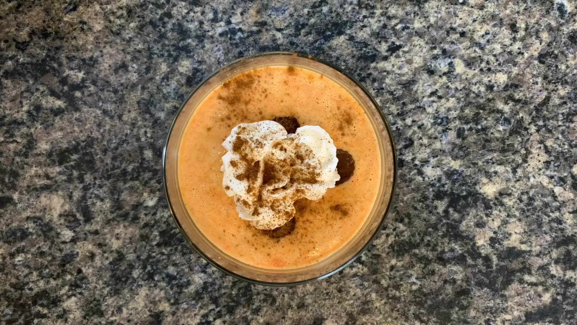 Warm carrot cheesecake protein oatmeal topped with whipped cream and cinnamon in a glass bowl.