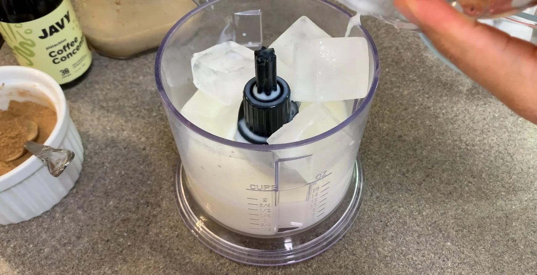 Food processor filled with milk, ice, coffee, and pumpkin sauce ready to blend for a frappuccino.
