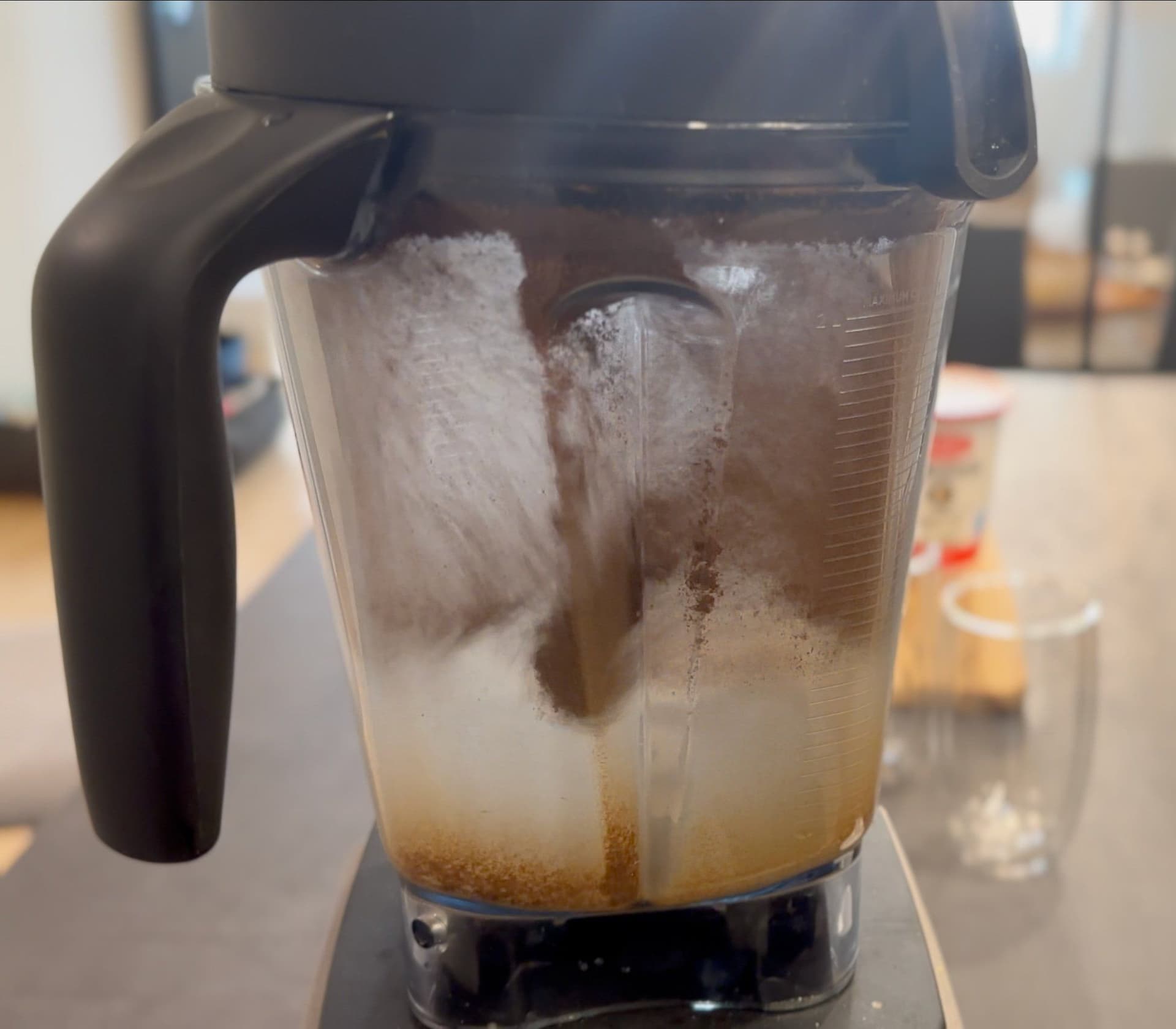 Blender pitcher containing yogurt drink mixture being blended with ice and roasted cumin powder.