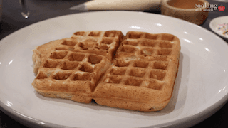 Two golden sugar cookie waffles on a white plate with cinnamon glaze drizzle.