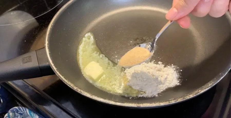 Butter, flour, and garlic powder being stirred together in a pan for béchamel sauce.