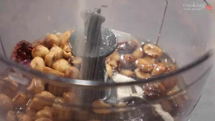 Blending roasted peanuts, tamarind, and spices in a food processor to make peanut chutney.