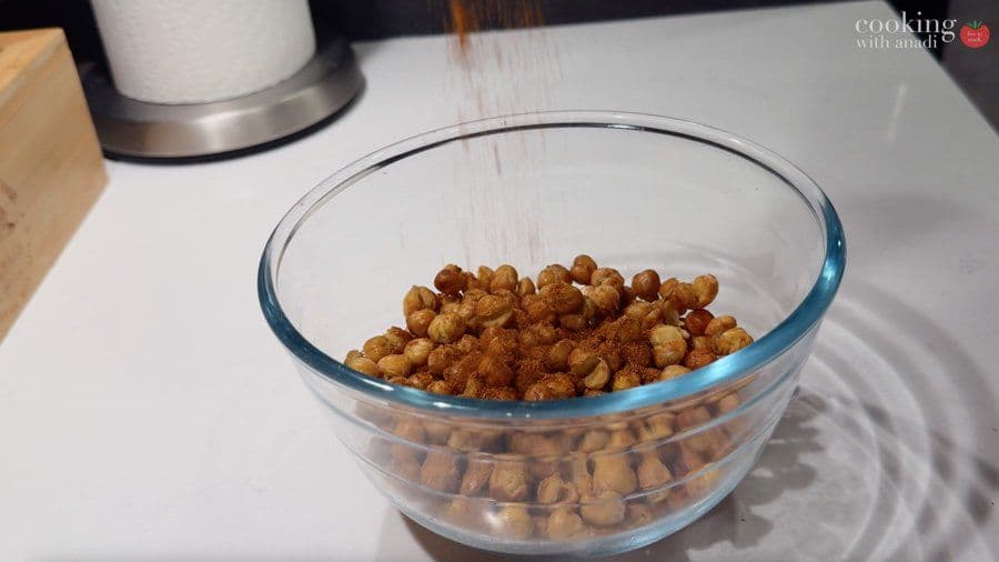 Crispy air fryer chickpeas coated with spices in a glass bowl, ready to cool before serving.