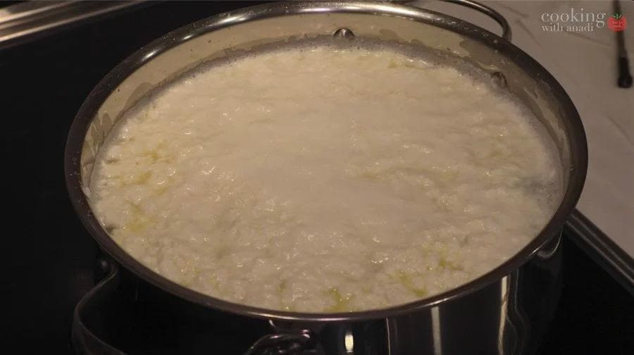 Milk curdling in a pot after adding buttermilk or lemon juice for homemade paneer making.