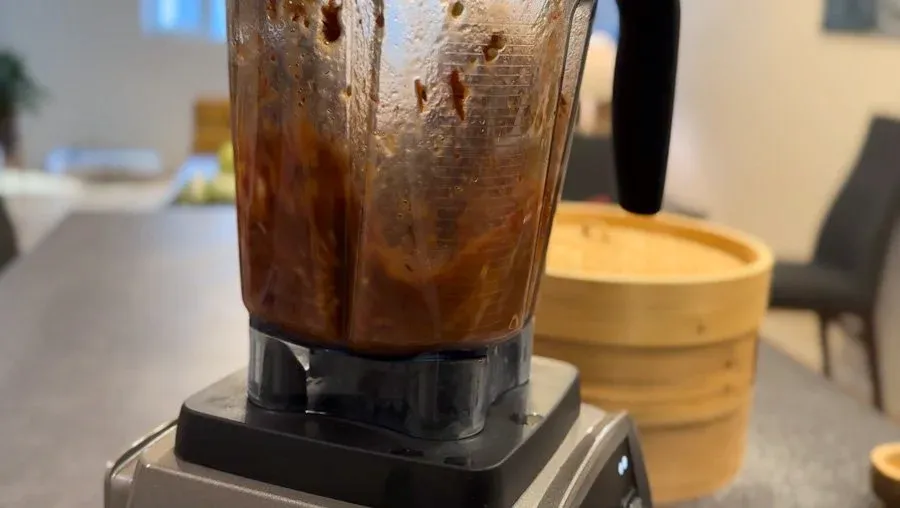 Spicy red chutney blending in a food processor, showing smooth brown-red mixture with visible ingredients.