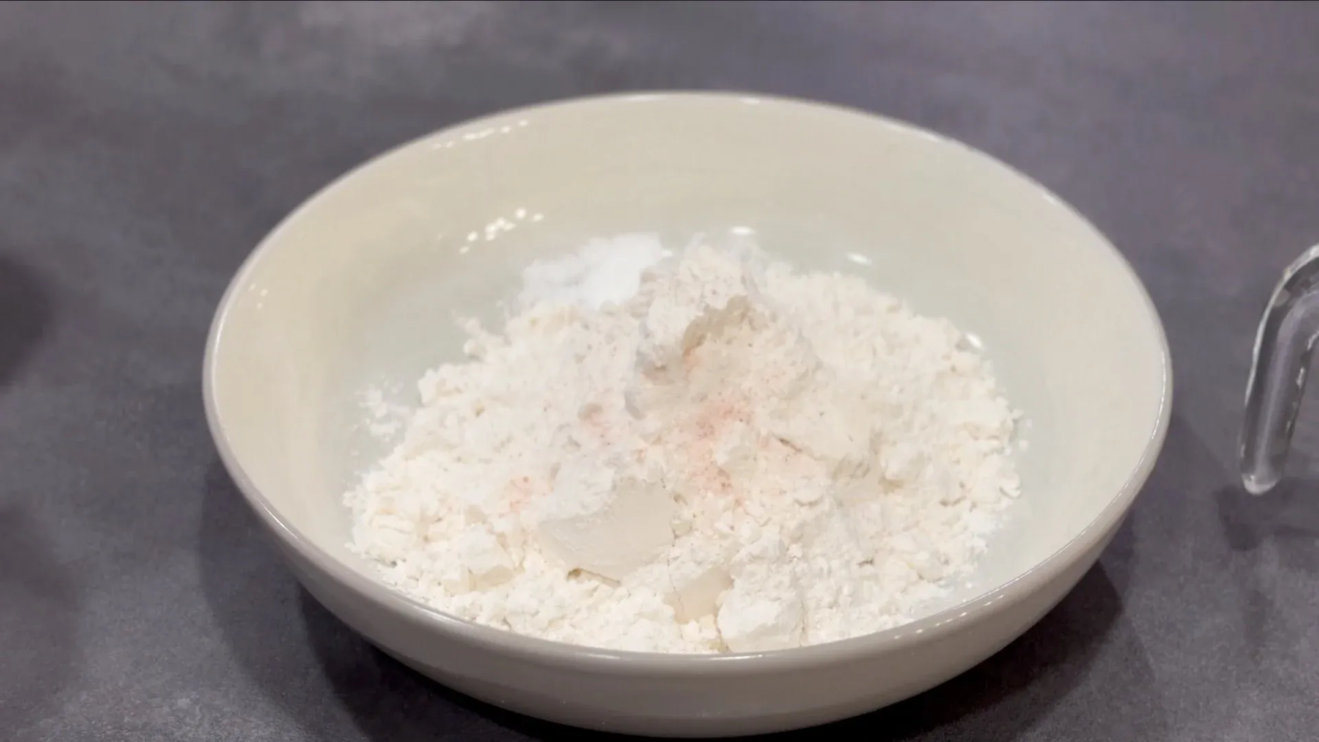 Dry ingredients for pie dough mixed in white bowl: flour, baking powder, salt, and shortening combined until crumbly.