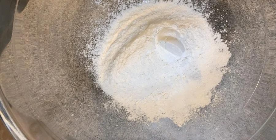Flour and baking powder mixed together in a large glass bowl for pancake batter.