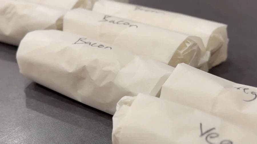 Breakfast burritos wrapped individually in parchment paper labeled with contents, ready for freezing.