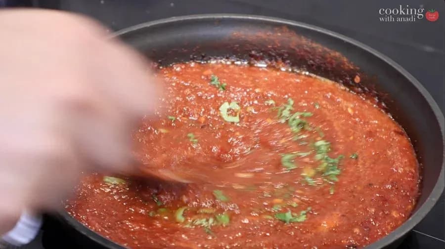 Simmering salsa roja in a pan, garnished with fresh cilantro and lime juice