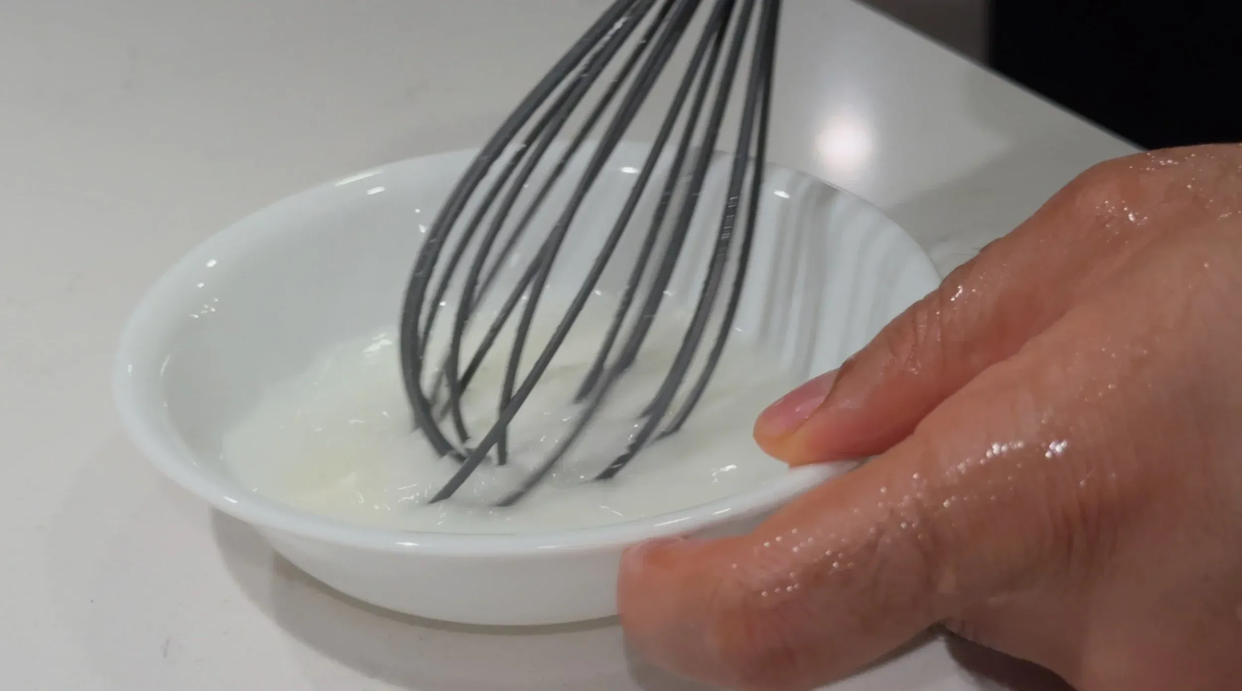 Cornstarch slurry being whisked in a small white bowl until smooth