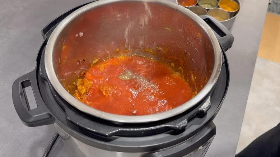 Instant Pot with rich red tikka masala sauce with visible spices and oil coating the surface.