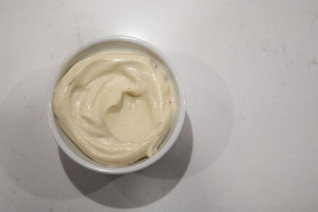 Creamy homemade mayonnaise in a white bowl with a swirled texture from an immersion blender.