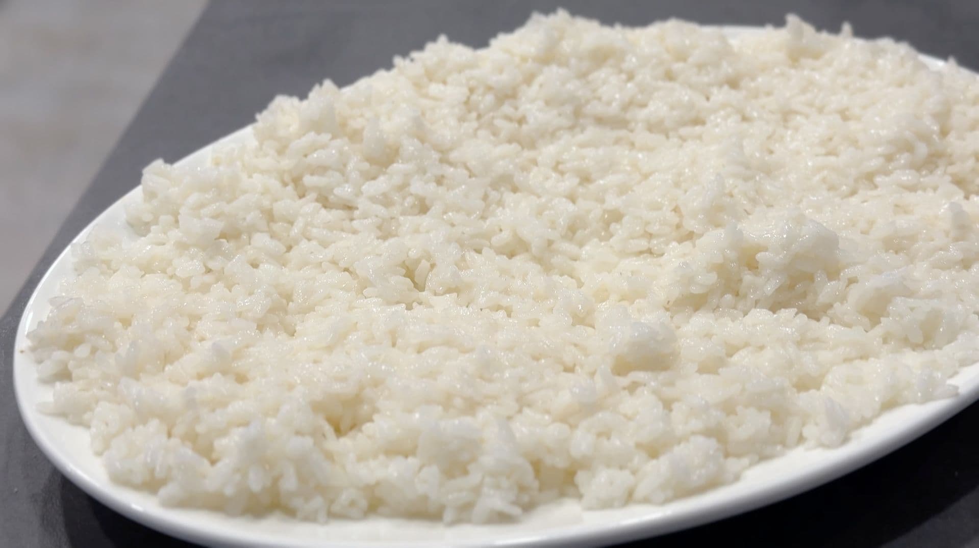 Cooked sushi rice in a fluffy, white mound on a white oval plate