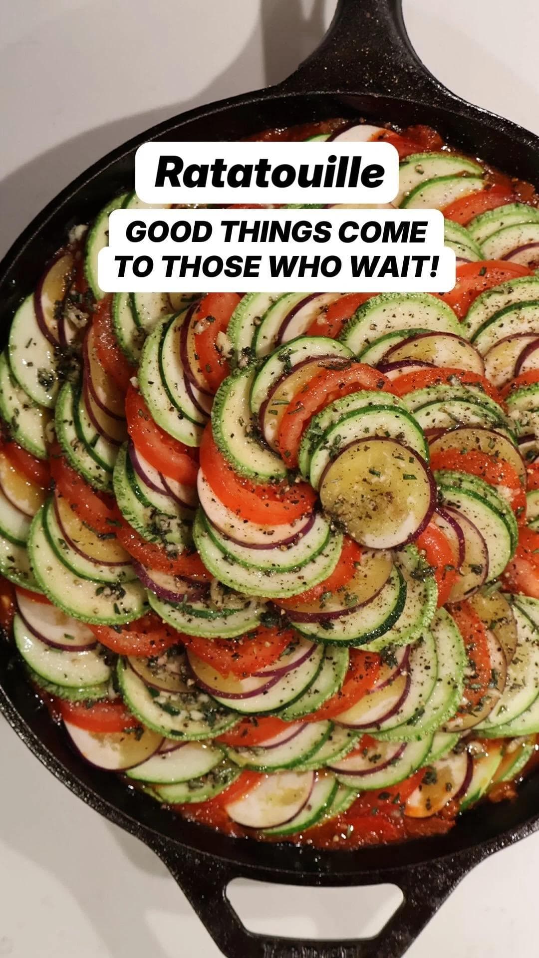 Ratatouille in a cast iron skillet with thinly sliced zucchini, tomato, and eggplant arranged in a spiral pattern.