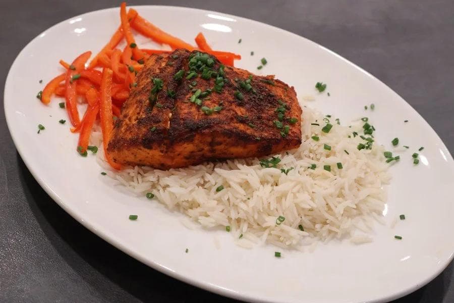Air fryer salmon fillet with spiced crust, served over white rice with julienned red peppers and fresh chives.