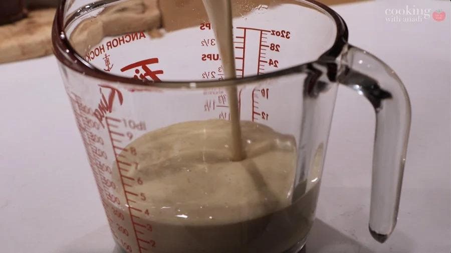 Pumpkin crepe batter being poured into a measuring cup with measurement markings visible.